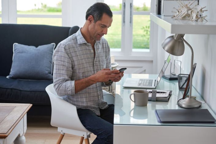 caucasian casual man working from home with laptop and cell phon