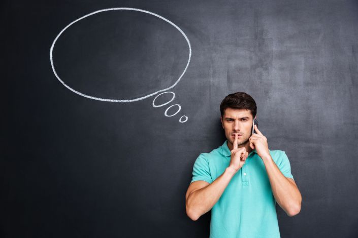 Man talking on cell phone and showing silence gesture