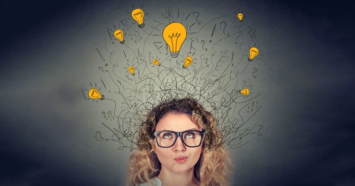 Thoughtful woman in glasses with many ideas light bulbs above head
